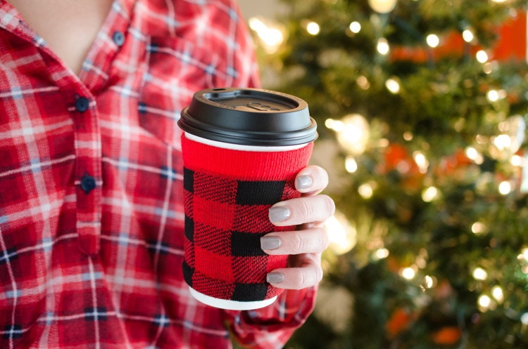 A person holding a cup with a koozie on it.