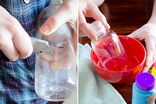 A person cutting the bottom of a plastic bottle.