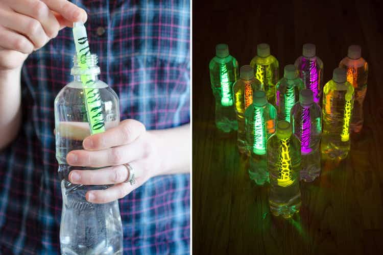 A person putting a glow stick in a bottle.