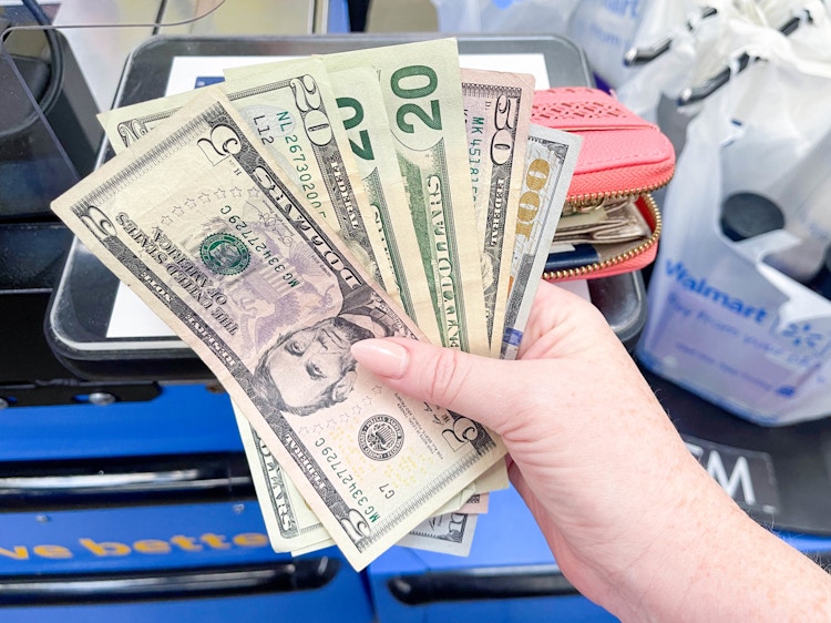 a person holding cash to pay for groceries