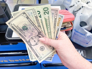 a person's hand holding up cash.