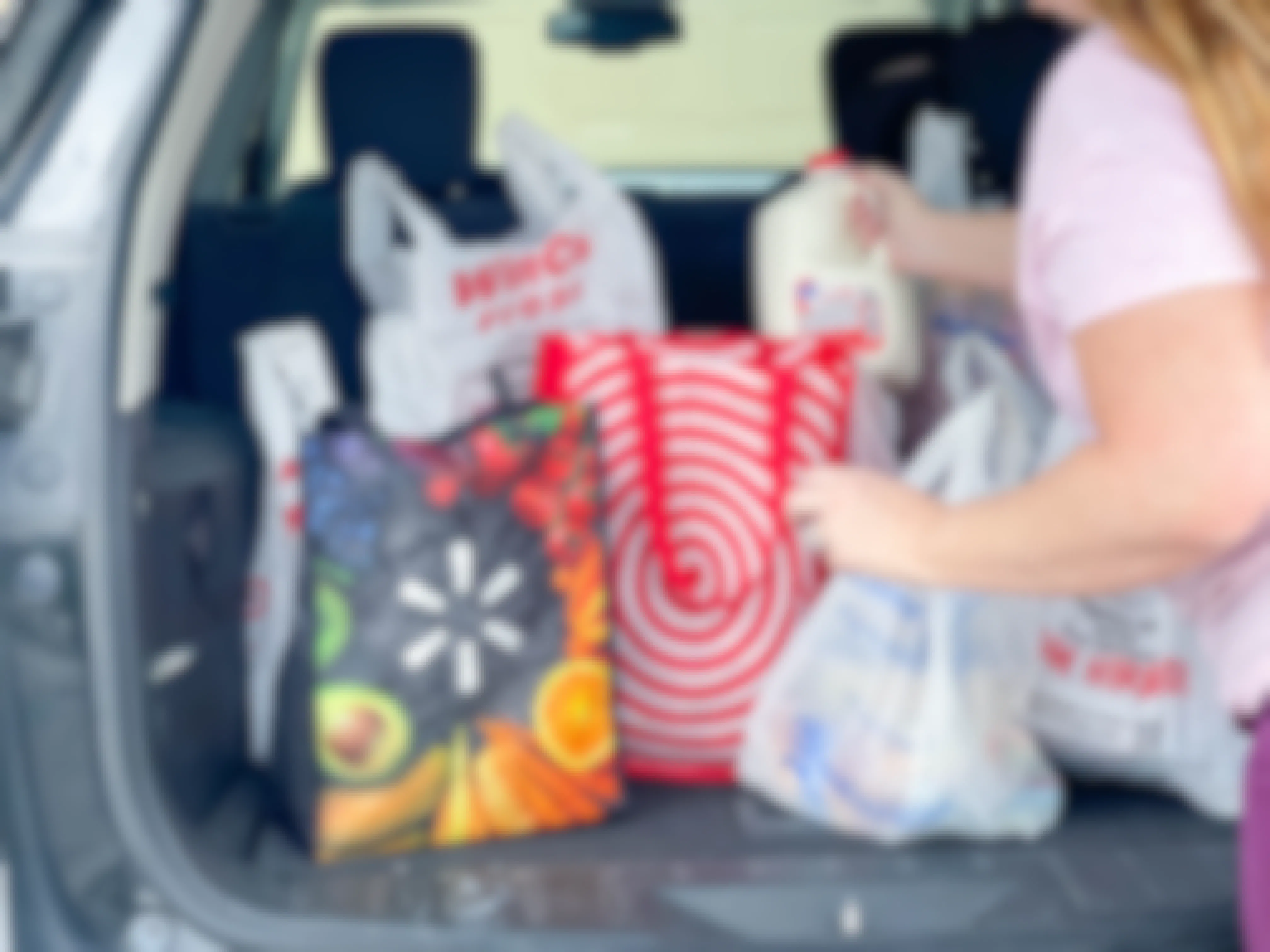 a person unloading a back of the car full of grocery bags