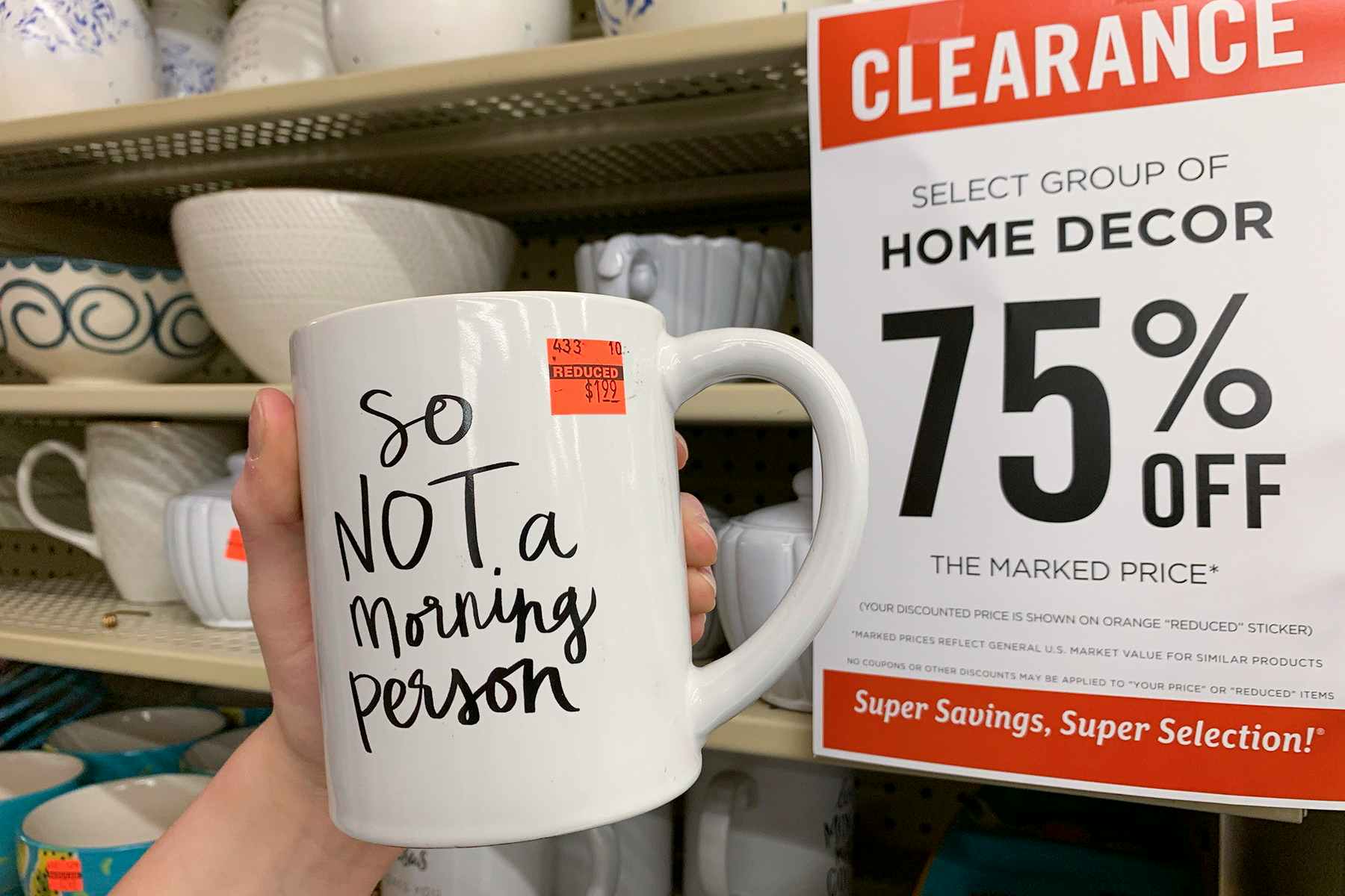 A mugA mug that says "so not a morning person" with a red clearance sticker stuck to it, held up next to a clearance sign that ready "home decor 75% off".