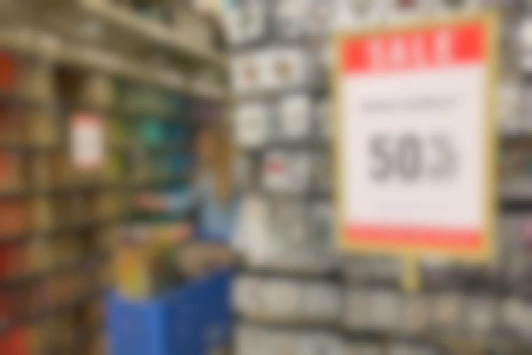 A sale sign on an end cap that reads "50% off". A woman can be seen in the background shopping for beads.
