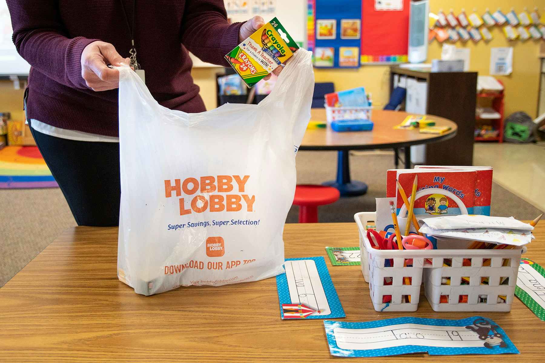 A box of Crayola Crayons being pulled from a Hobby Lobby shopping bag in a grade school class room.