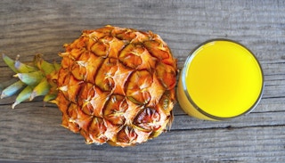 whole pineapple and glass of juice