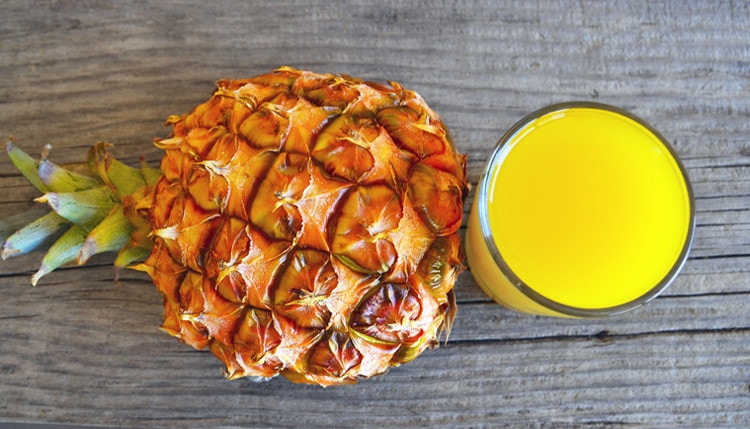 whole pineapple and glass of juice