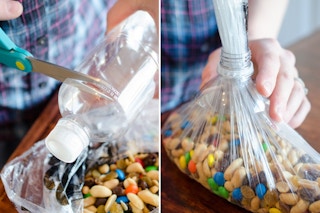 A person cutting a plastic bottle next to a person sticking the end of a bag through the lid of a cutoff bottle top.