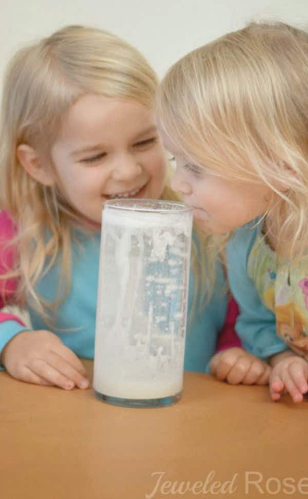 two girls look into a jar filled with scientifically created fake snow