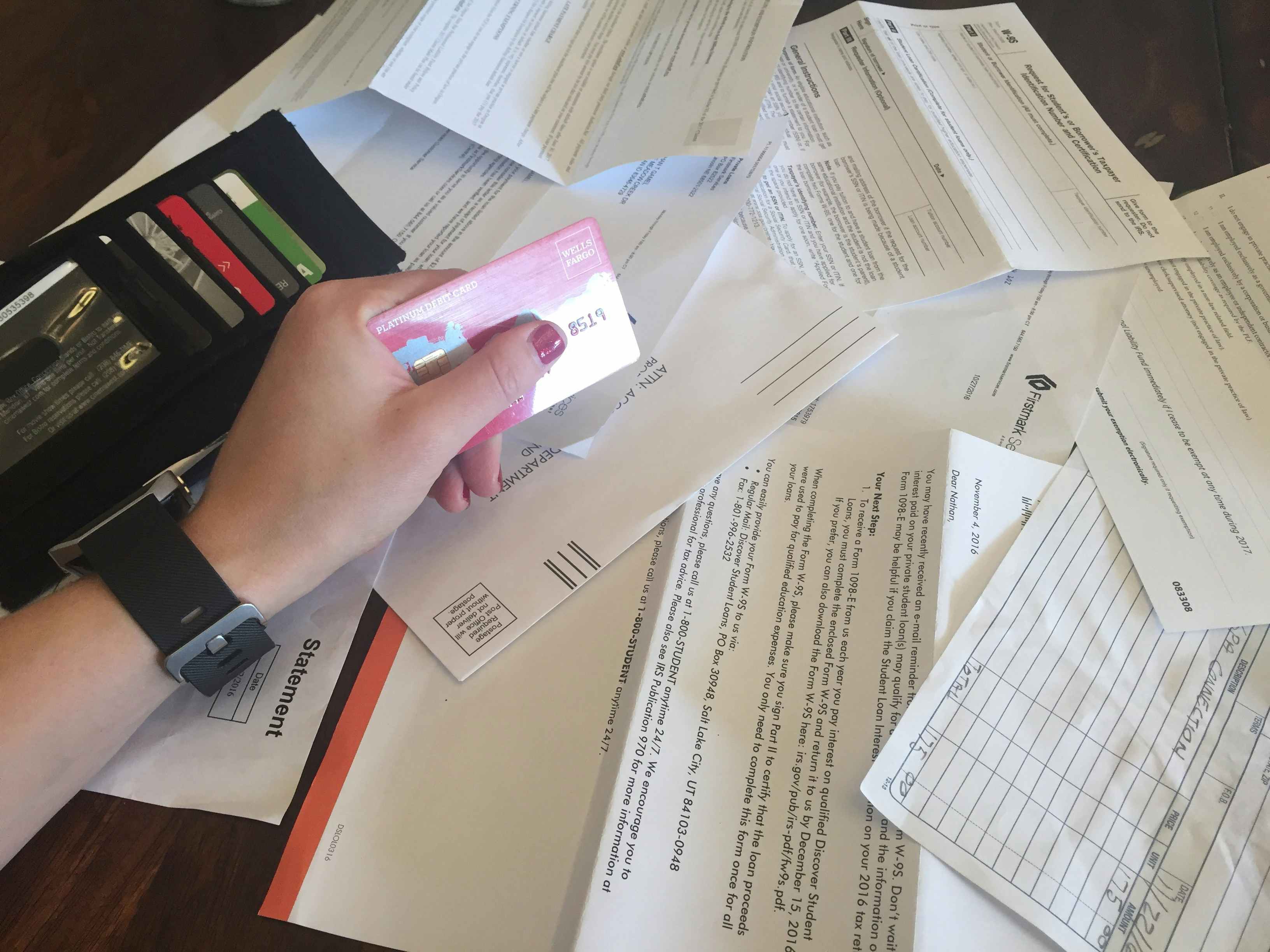 Woman holding a credit card with wallet and bills on table