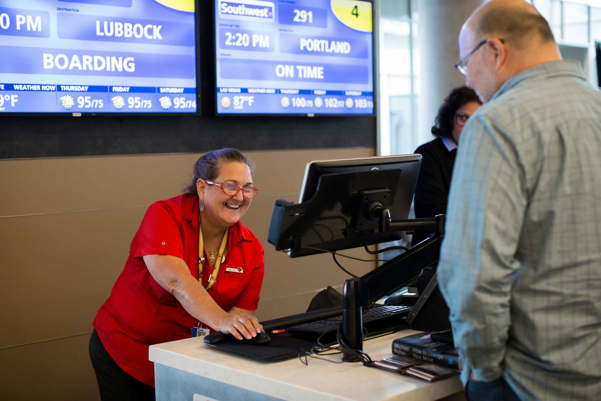 A Southwest employee at the gate desk talking to passengers.