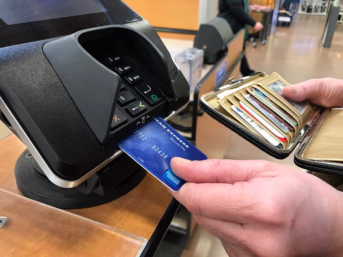 A person putting a credit card into the credit card machine at checkout.
