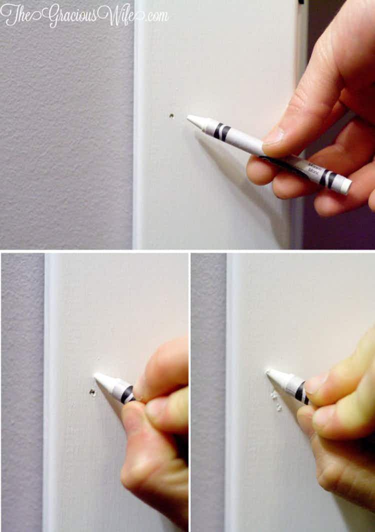 someone drawing over a nail hole with white crayon