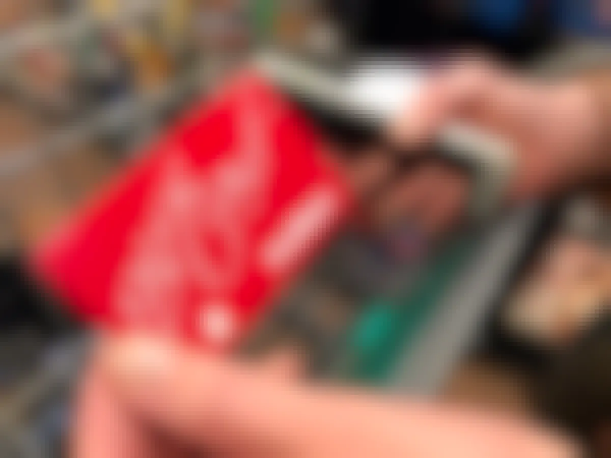Woman holding fred meyer gift card while shopping in store.