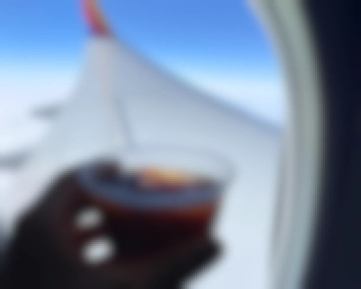 hand holding a mixed drink on Southwest flight near window