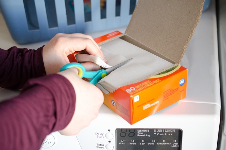 Someone cutting a box of dryer sheets in half.