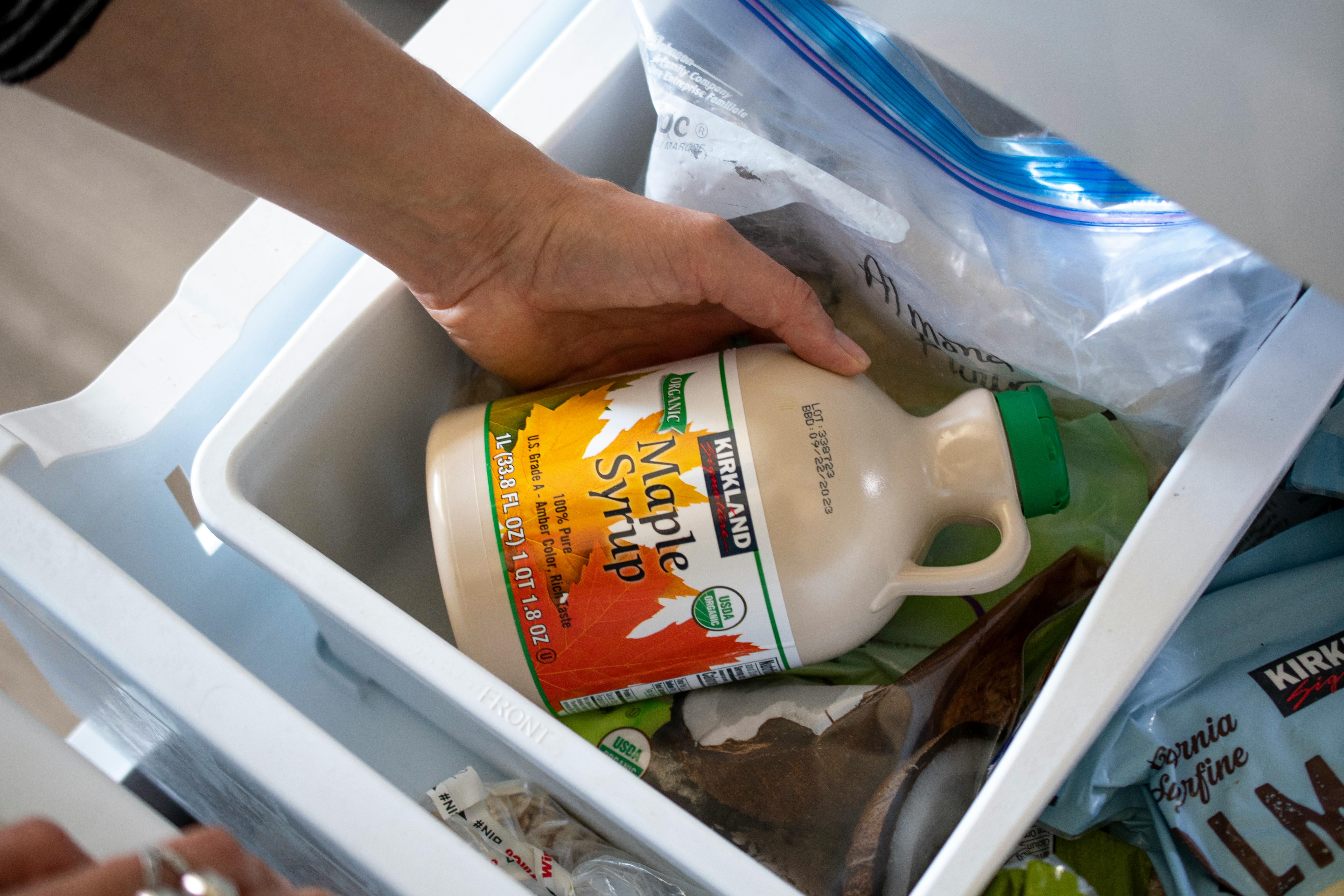 A person pulling a container of pure maple syrup from the freezer