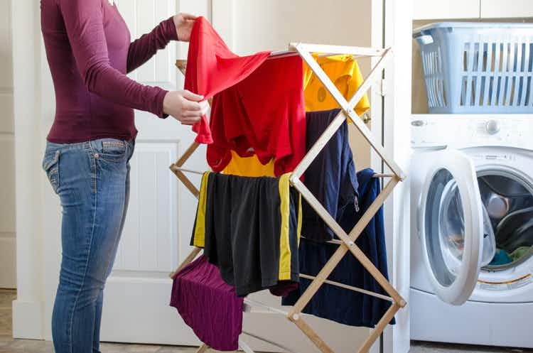 A person hanging clothes to dry on racks.