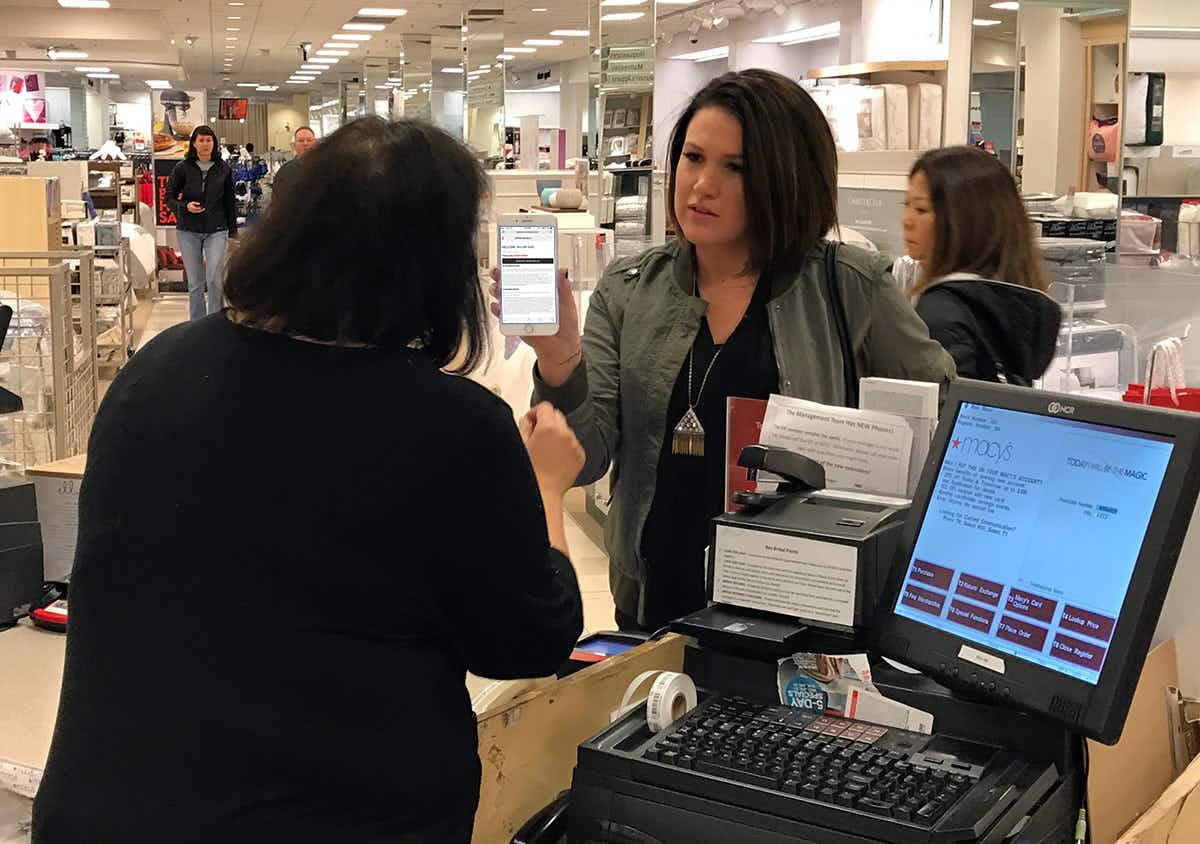 woman showing phone to cashier at checkout