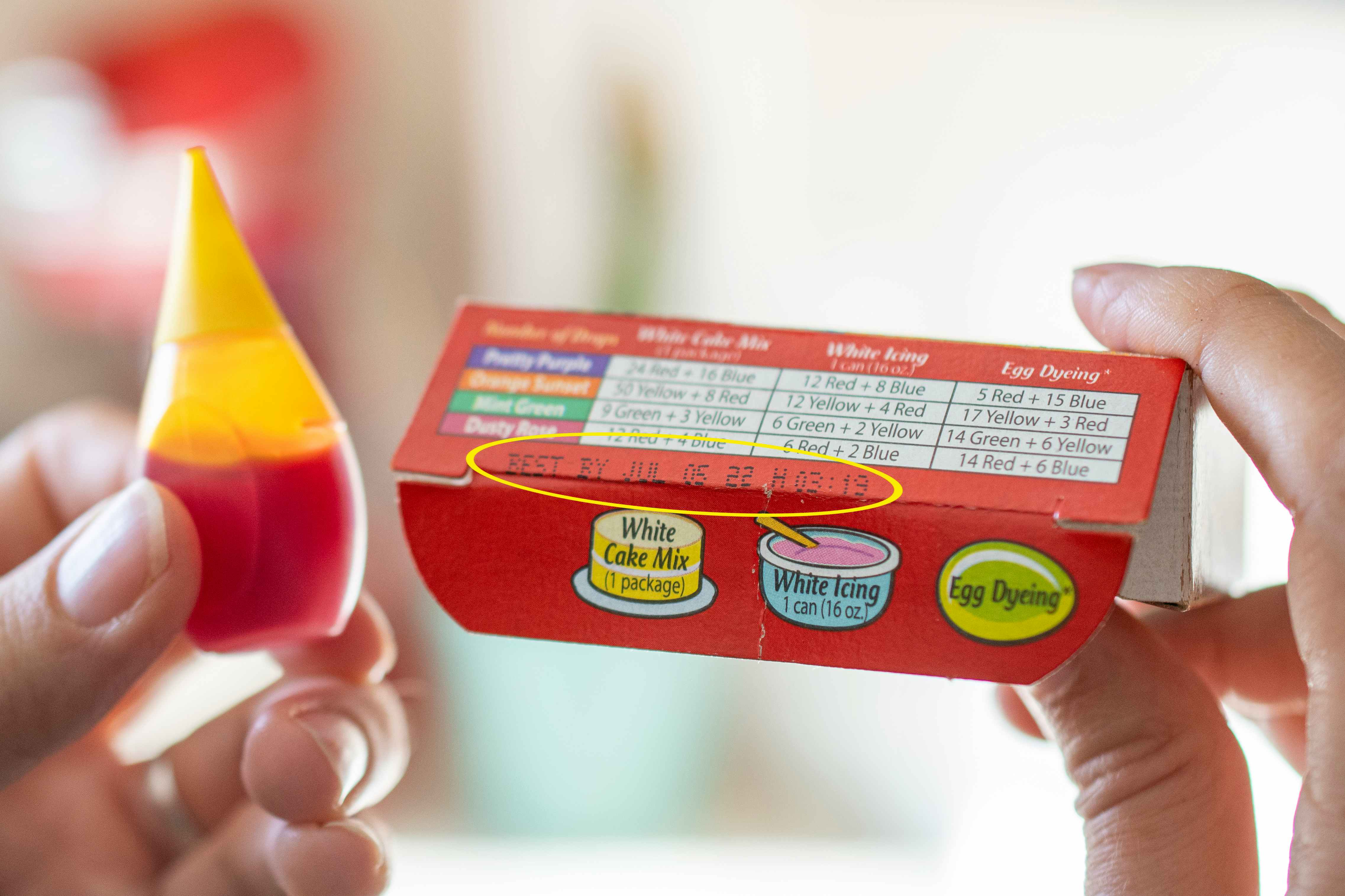 A food coloring box next to a bottle of yellow food coloring. A yellow circle is around the expiration date.