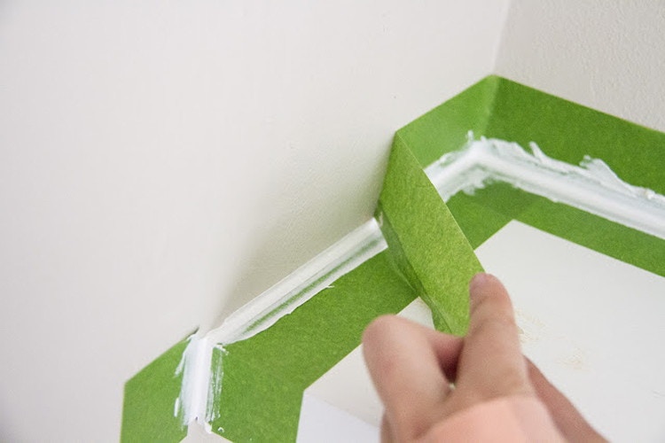someone pulling painters tape off wall