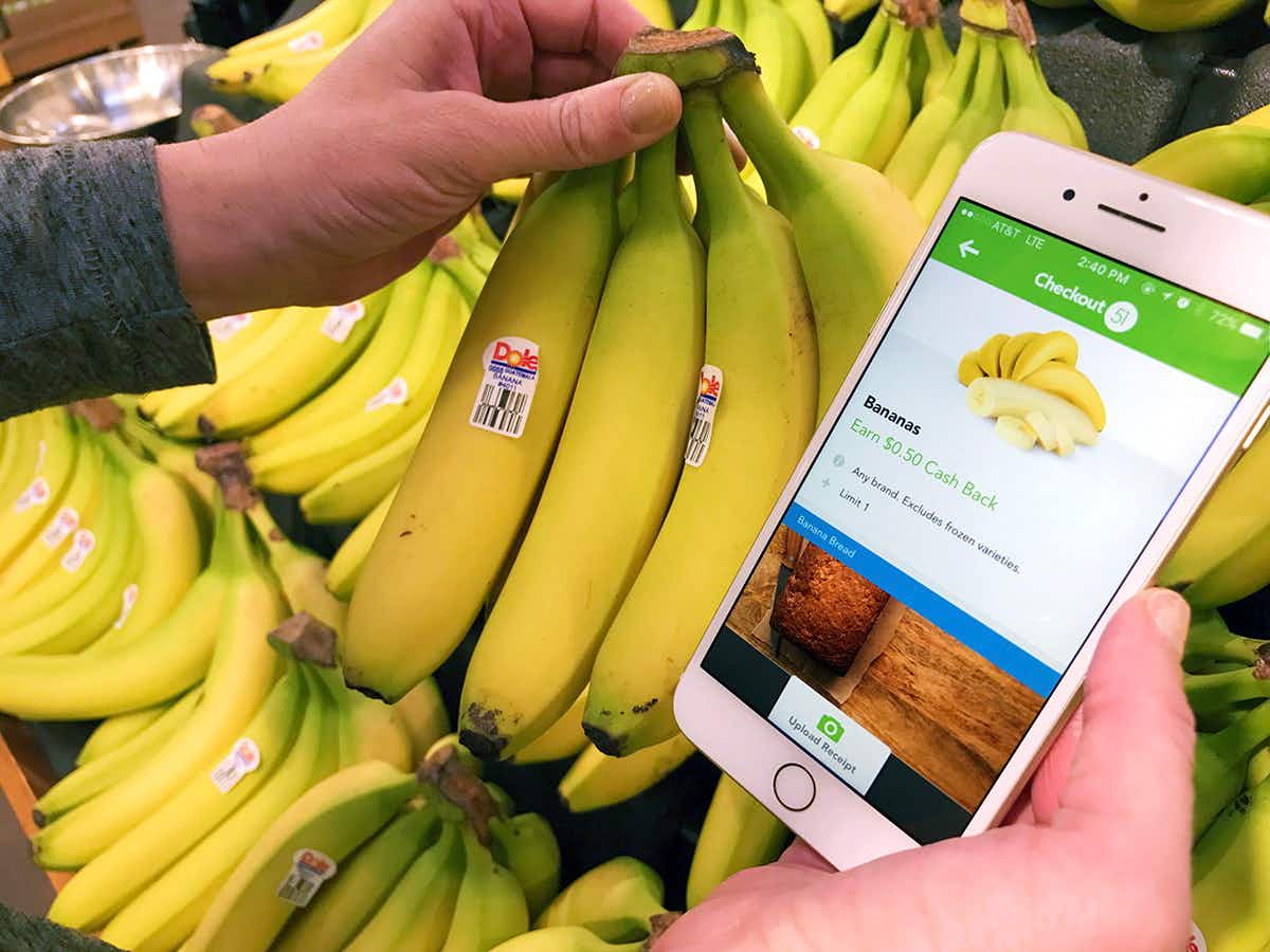 A cell phone showing a banana offer on Checkout 51, next to a bunch of bananas. 
