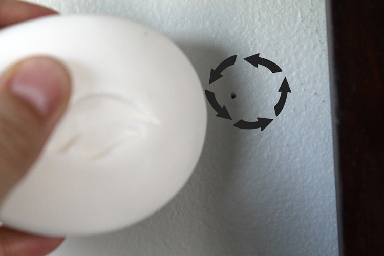 someone using bar of soap to cover a nail hole