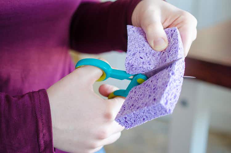 Person using scissors to cut a sponge and a half