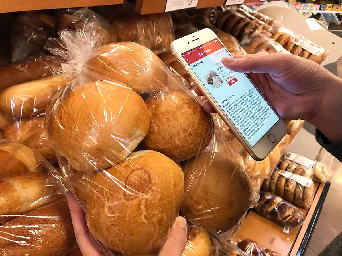 A bag full of rolls with the store's app next to them.