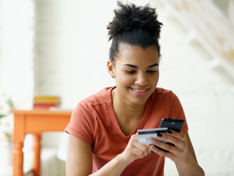person looking at phone and holding credit card