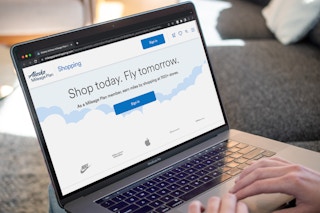 A person looking at the Alaska Airlines Mileage Plan Shopping website on a laptop