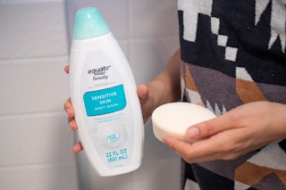 A person holding a bar of soap and a bottle of body wash