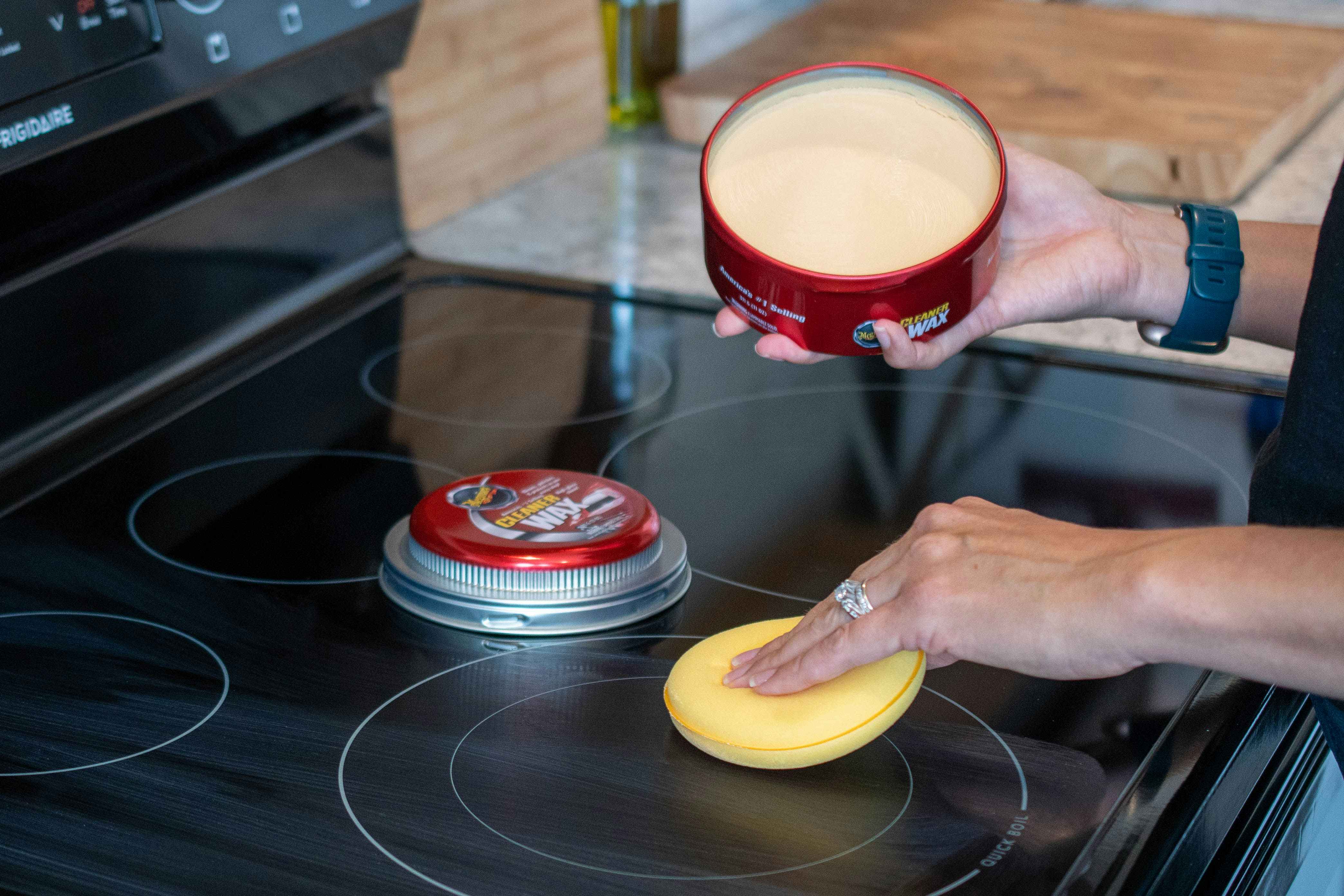 A glass cooktop stove being polished with Car Wax