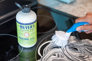 A stove being cleaned with Mrs Meyers Clean Day baking soda cream cleaner