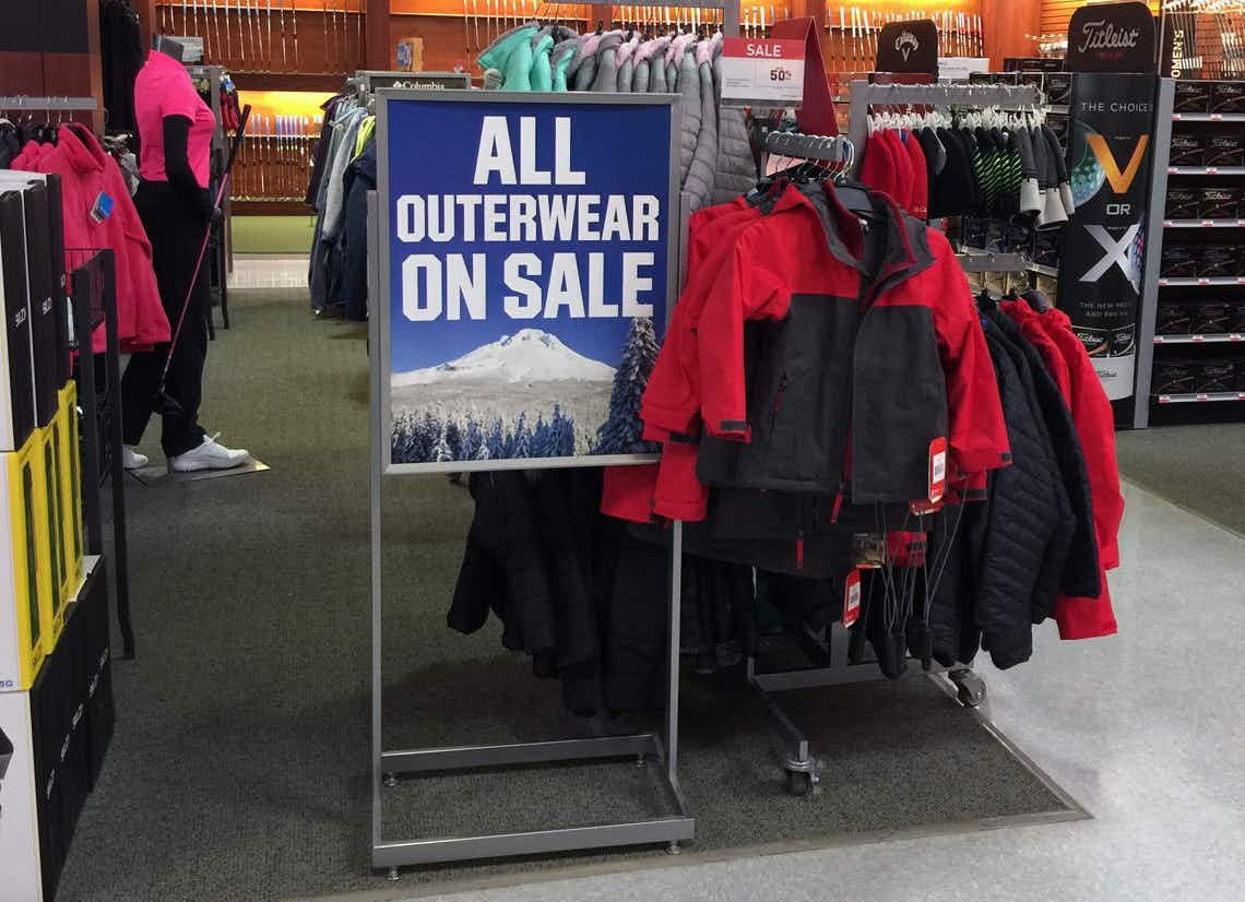 A sign that says "All outerwear on sale" next to a rack of winter coats at Dick's Sporting Goods