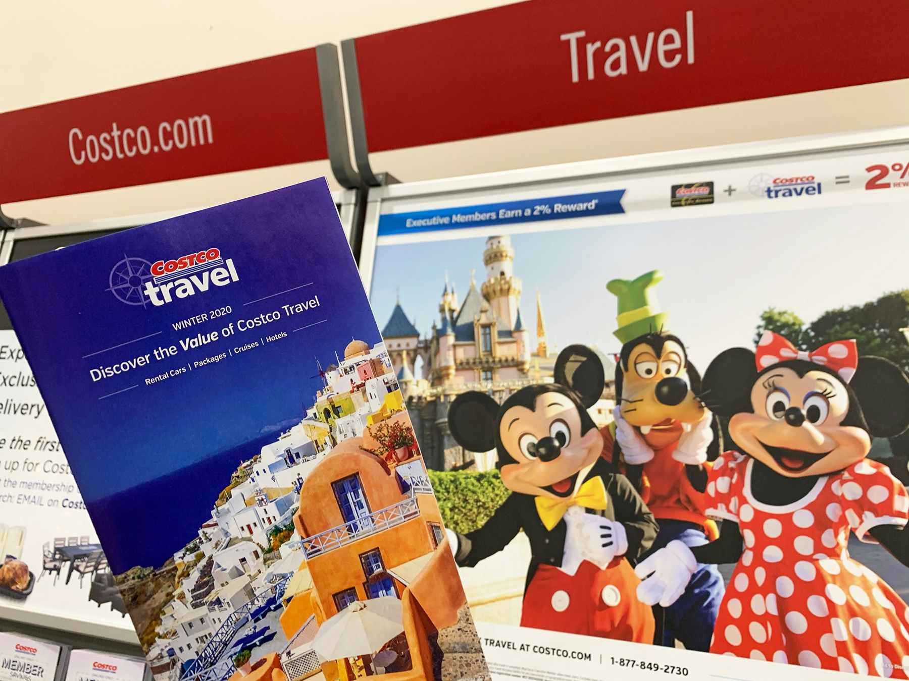 A costco travel pamphlet in front of a Disney sign showing Mickey, and Minnie in Costco.
