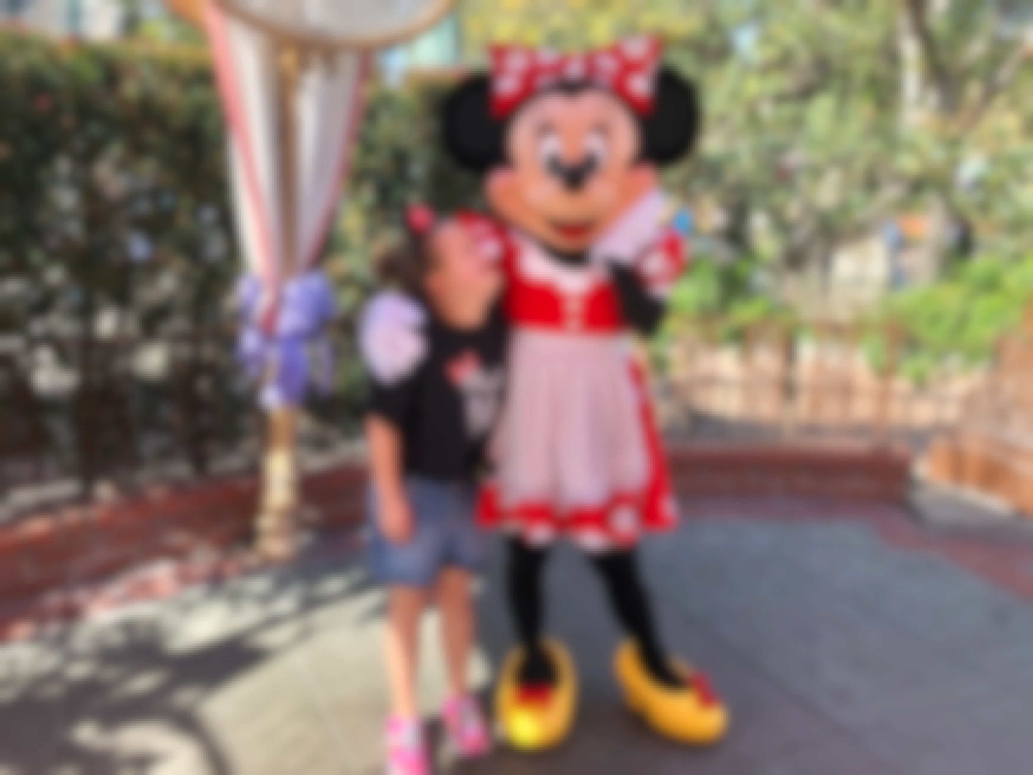 A little girl poses with Minnie Mouse at Disneyland.