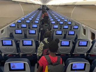 A family walking down the aisle of an airplane to their seats.