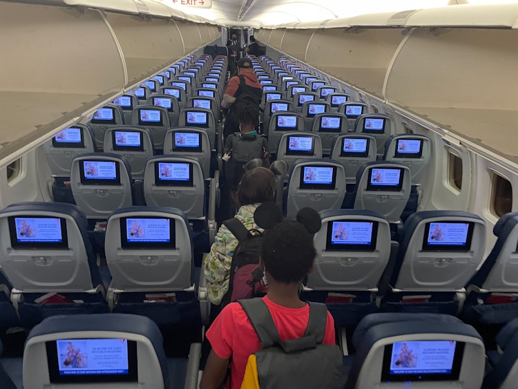 A family walking down the aisle of an airplane to their seats.