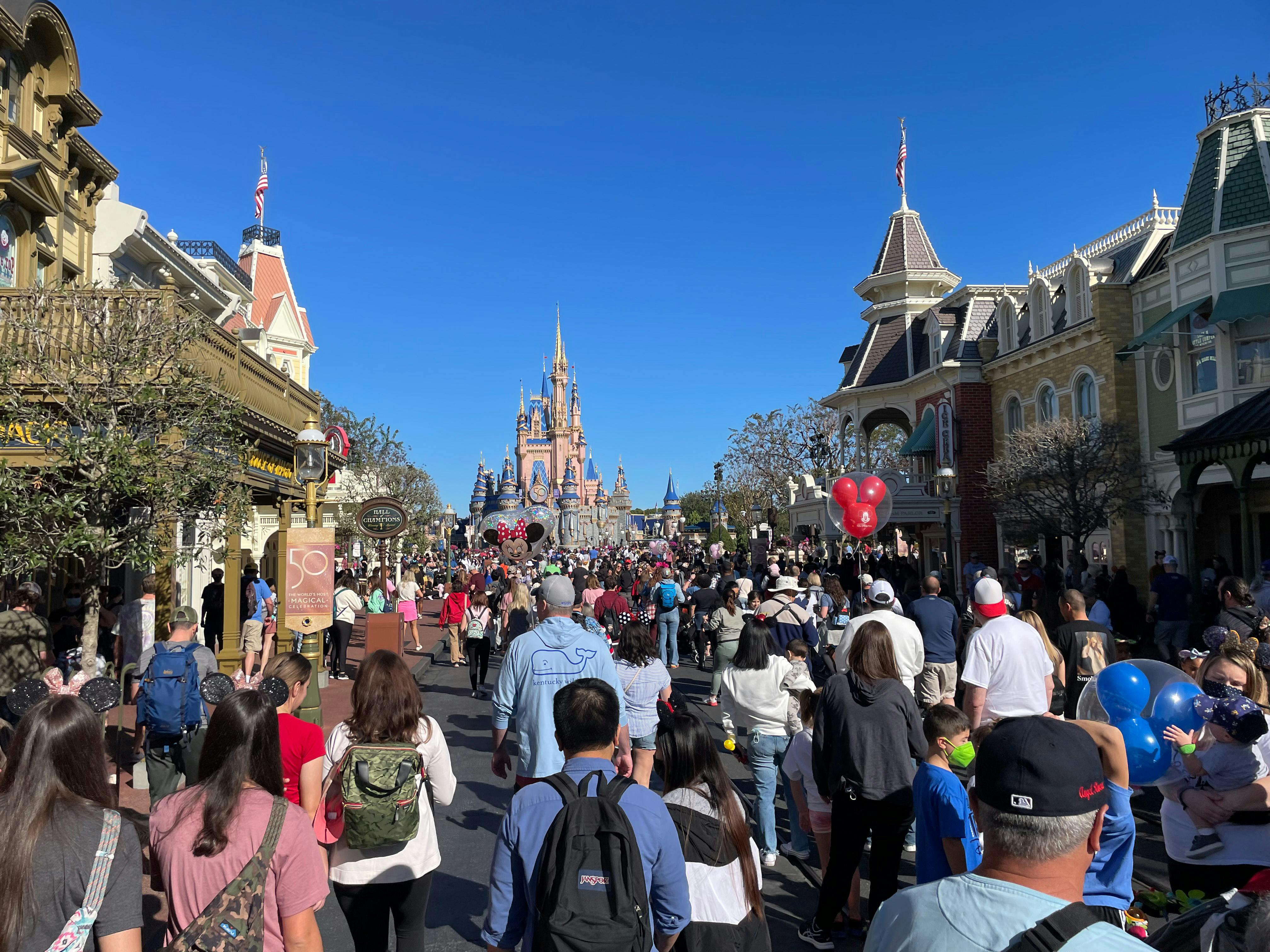 A crowd on the main street in front of the Magic Kingdom Castle at Disney World.