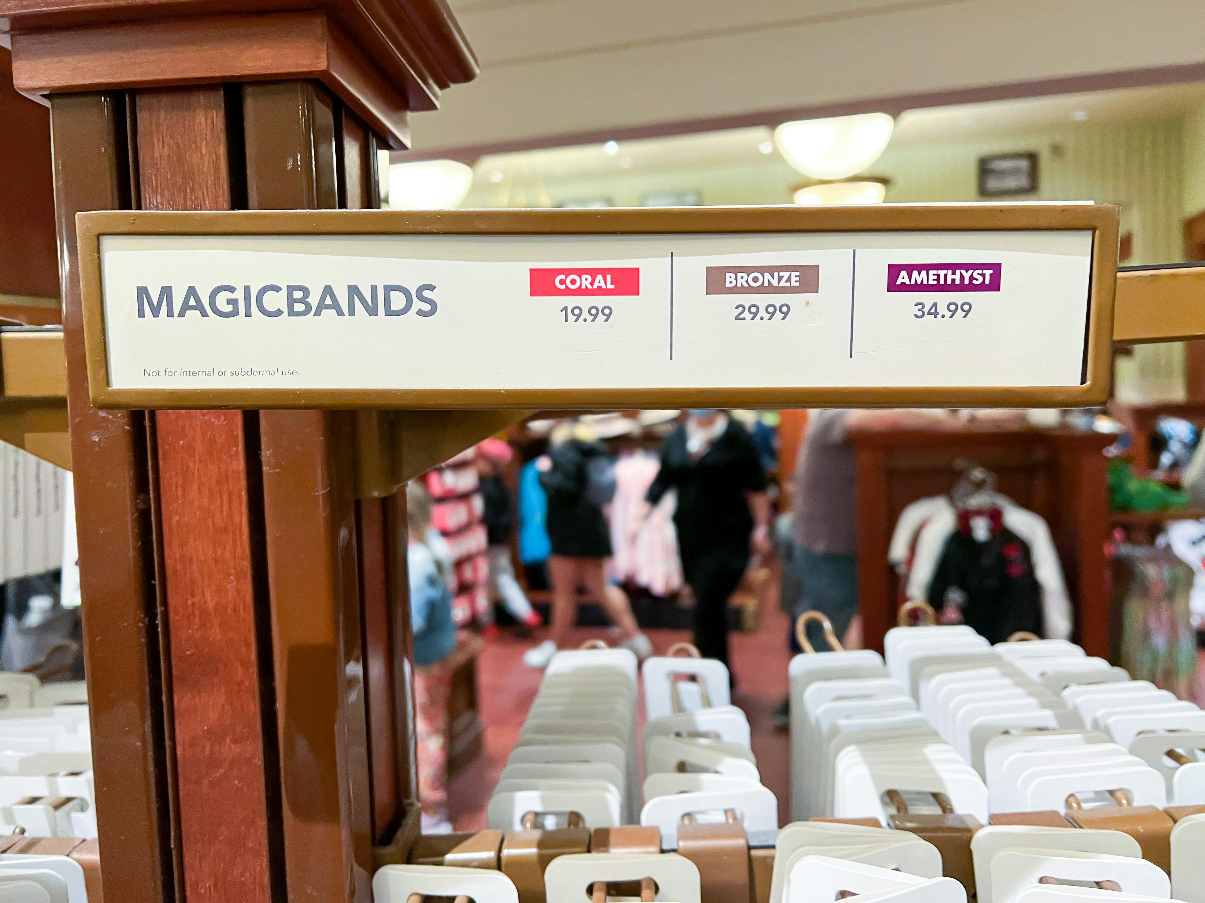 A shelf inside a Disney World store with MagicBands, and a sign showing the prices for each kind.