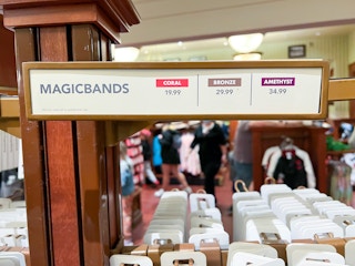 A shelf inside a Disney World store with MagicBands, and a sign showing the prices for each kind.