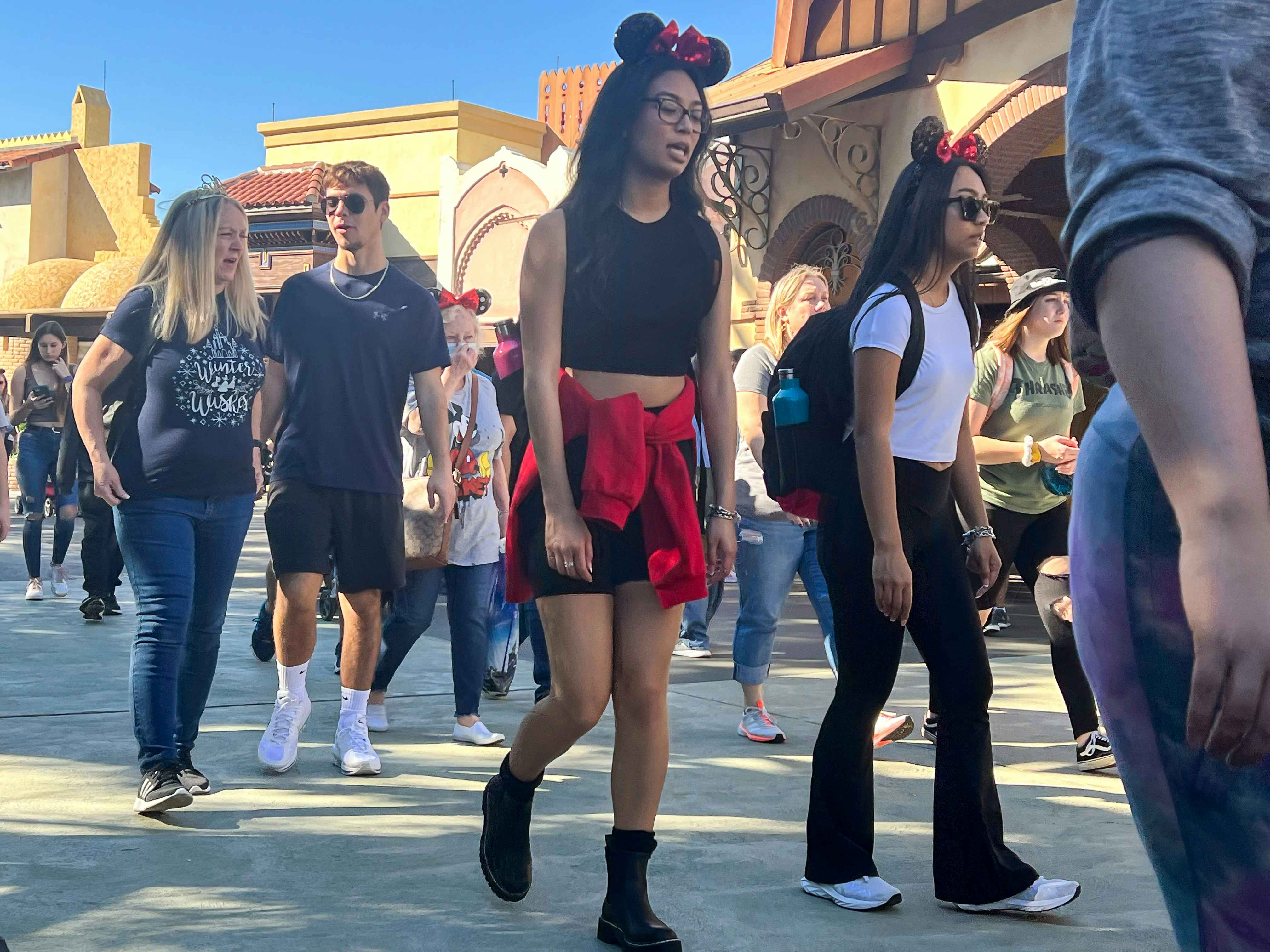 Patrons walking through a crowd at a Disney park.