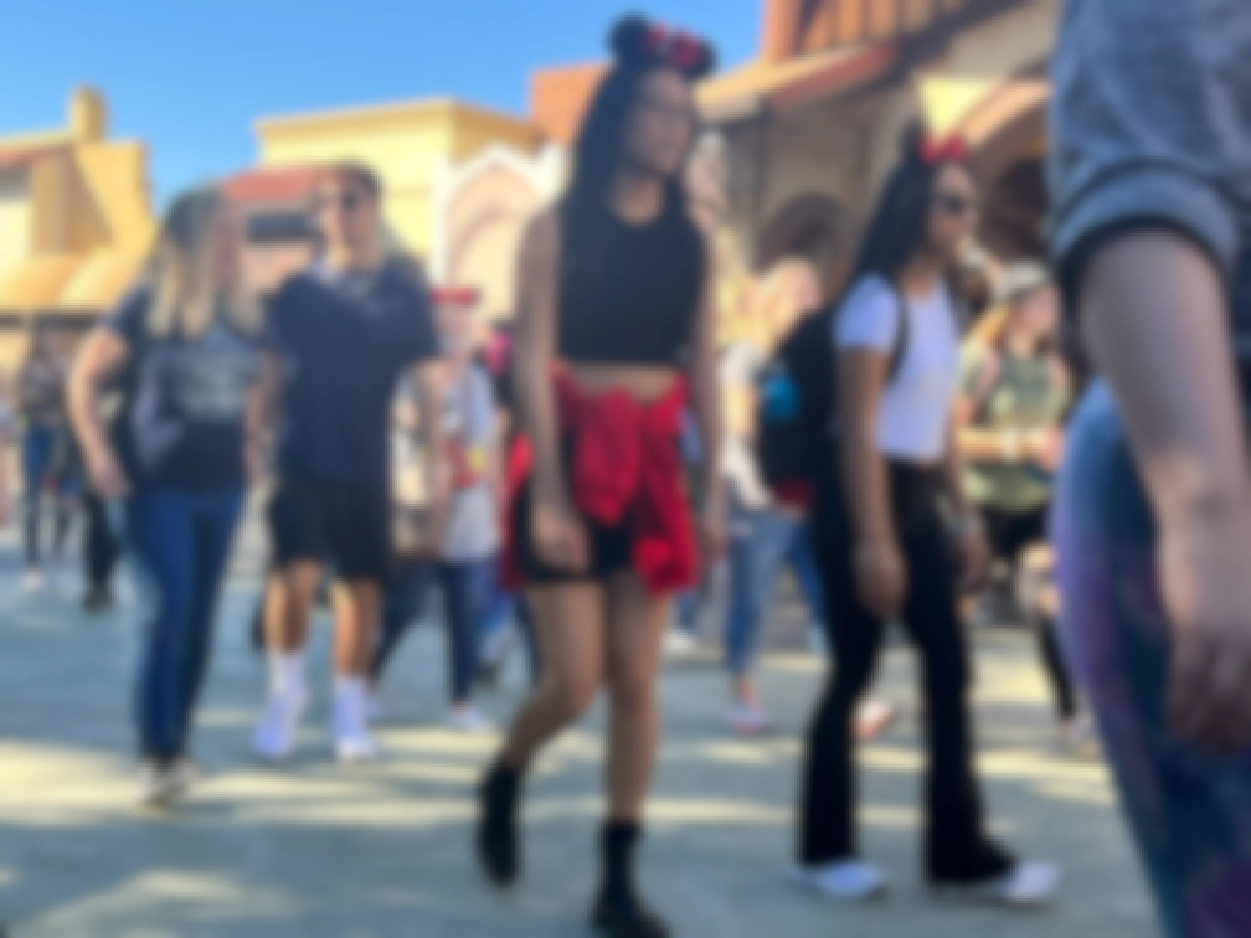 Patrons walking through a crowd at a Disney park.