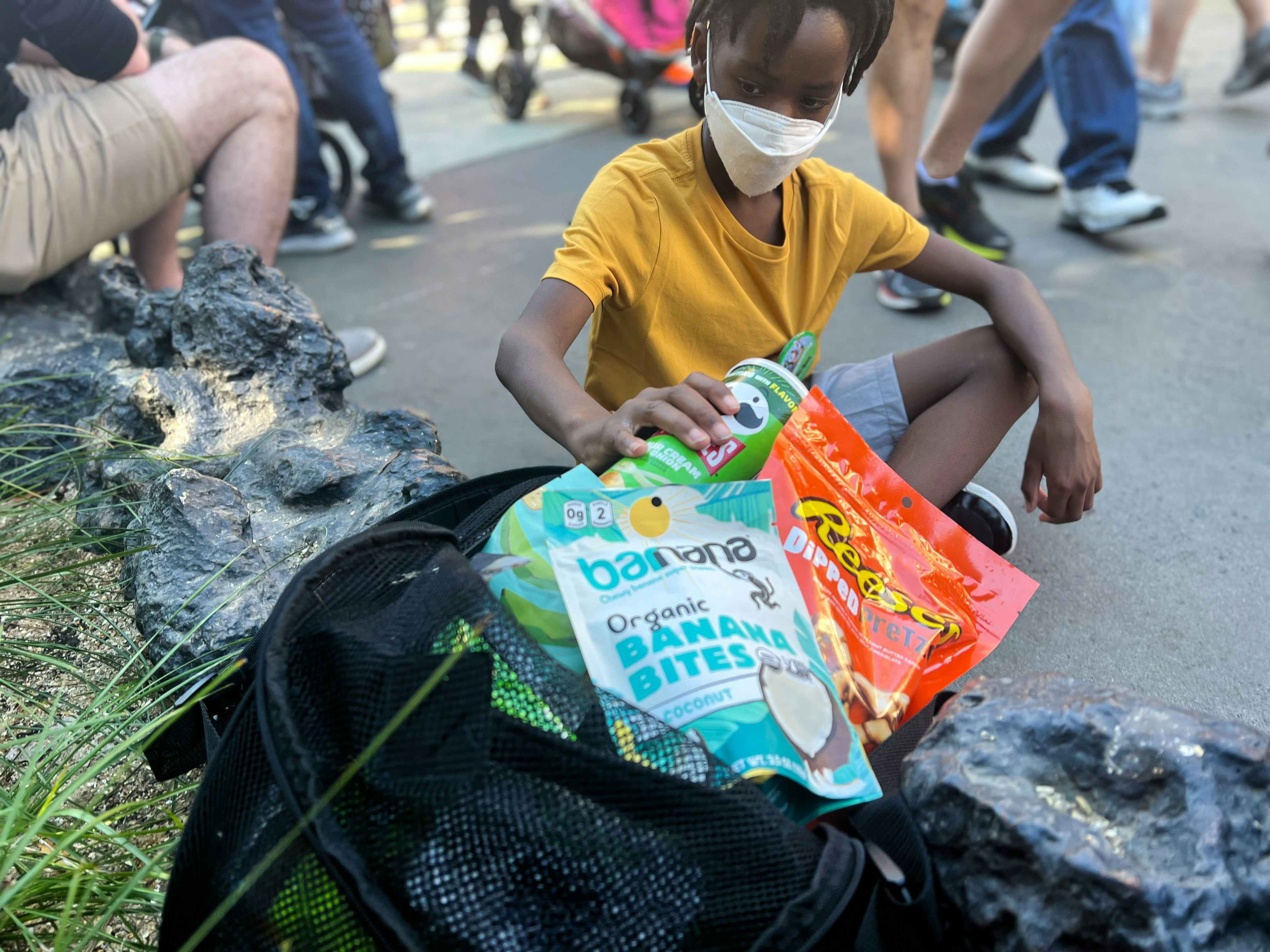 A child taking a can of Pringles out of a bag full of snacks.