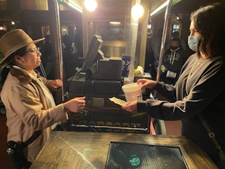 A person handing their souvenir popcorn container and a receipt to a Disney employee to get a $2 refill.