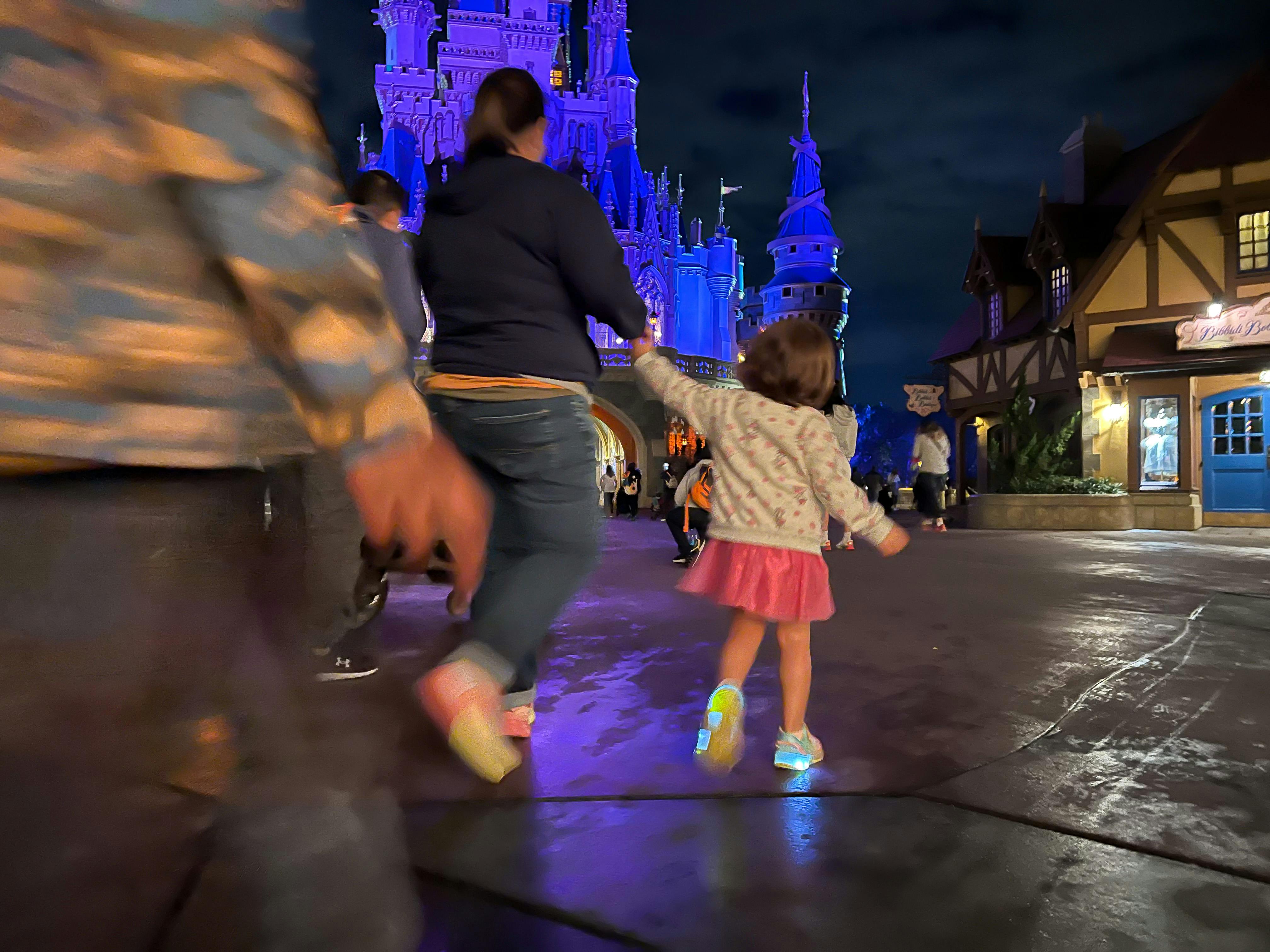 A mom and her child walking in front of the Magic Kingdom castle at Disney World.