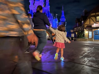 A mom and her child walking in front of the Magic Kingdom castle at Disney World.