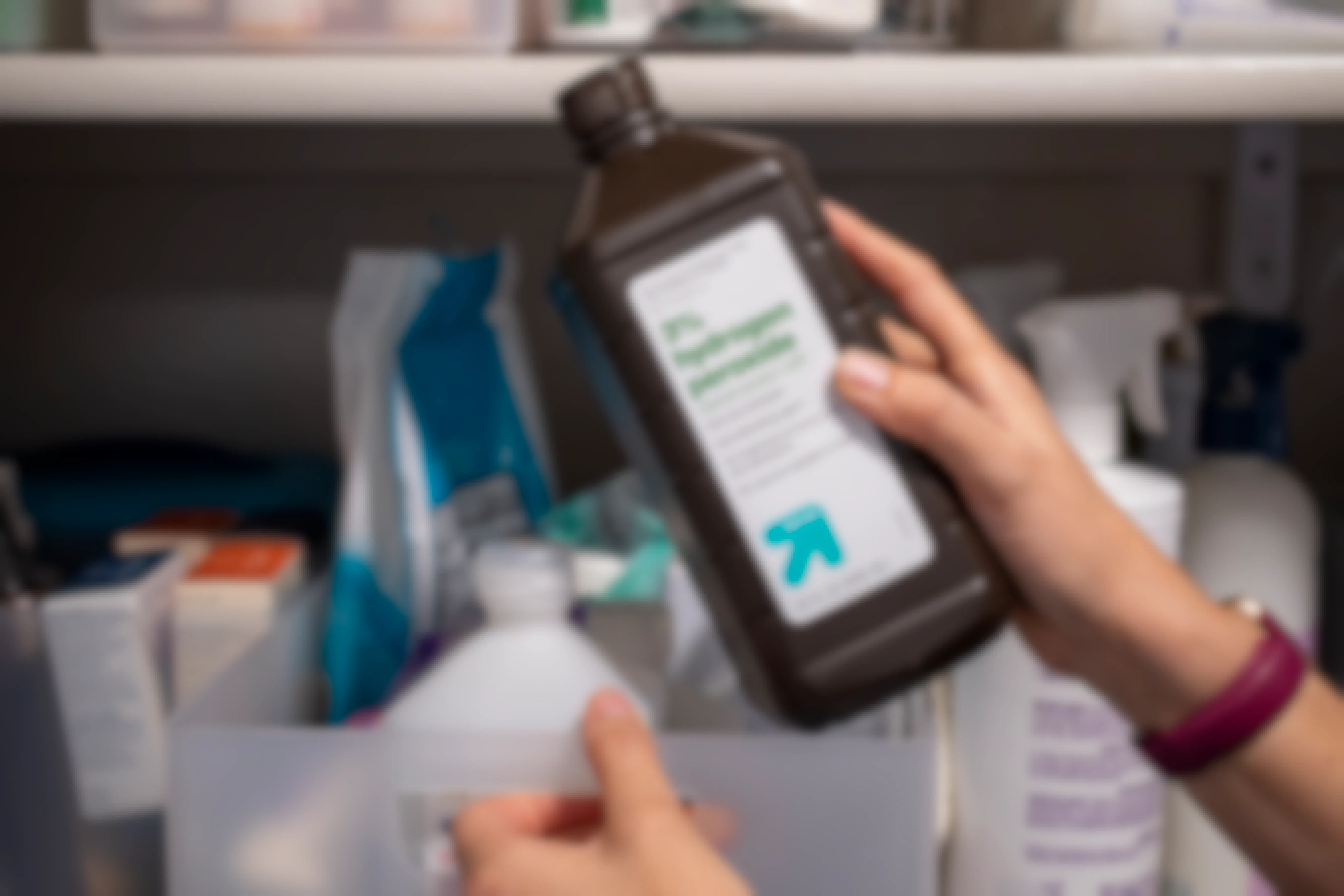 A woman pulling a bottle of hydrogen peroxide from a linen closet shelf