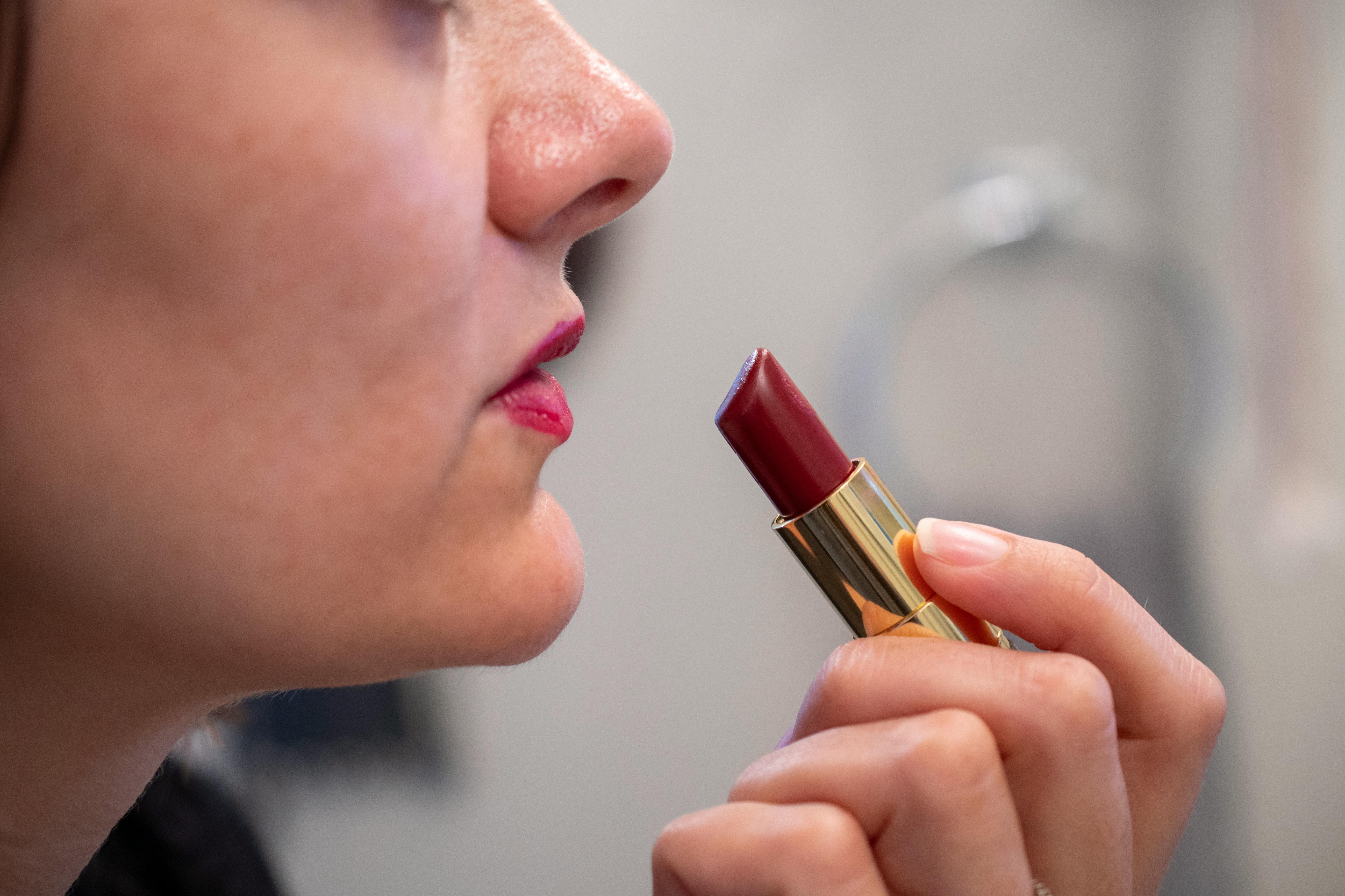 A woman putting on red lipstick